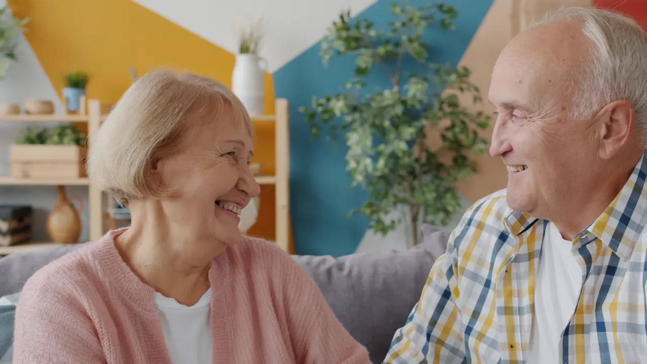 Älteres Paar lacht zusammen im Wohnzimmer